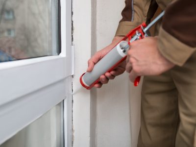 Close-up Of Person Hands Applying Silicone Sealant With Caulking Gun